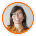 Smiling person with shoulder-length dark hair and glasses, wearing an orange shirt, inside an orange circle frame with a light gray background.
